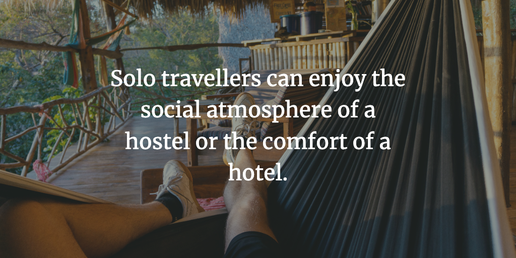 A man lies in a hammock at a hostel. The text reads, 'Solo travellers can enjoy the social atmosphere of a hostel or the comfort of a hotel.'